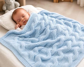 May include: A light blue knitted baby blanket featuring a prominent cable knit pattern with wavy vertical columns. The blanket is rectangular with a ribbed border and is draped over a sleeping infant resting on a white pillow.
