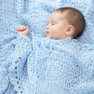May include: A baby sleeping peacefully while wrapped in a light blue, intricately crocheted blanket. The blanket features a delicate, open-work lace pattern with a scalloped edge, providing a soft and textured covering for the infant.