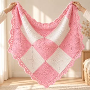 May include: A square crochet blanket featuring a checkerboard pattern of alternating soft pink and white yarn squares. The blanket is finished with a decorative scalloped crochet border in pink, creating a textured and uniform edge.