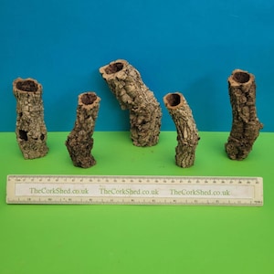 May include: Several pieces of cork bark, displaying a natural, textured appearance and hollow interiors. The bark is brown, with varying shapes and sizes. A ruler, marked in centimetres, with the text "TheCorkShed.co.uk" is at the bottom.