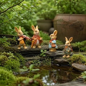 May include: Four anthropomorphic rabbit figurines standing on a mossy stone ledge. The first rabbit wears a black jacket and plays a violin. The second wears a brown coat and carries an umbrella. The third wears a blue coat and bag. The fourth wears a green outfit.