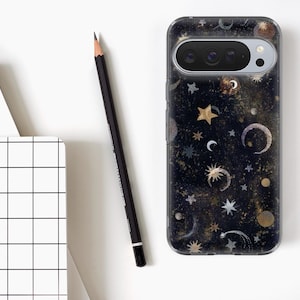 May include: A smartphone case with a celestial design featuring stars, moons, and planets in gold, silver, and white against a dark blue background. A black pencil and a white grid notebook are also in the image.