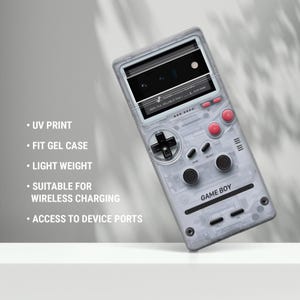 May include: A clear phone case with a retro video game design. The case features a black directional pad, red buttons, and the text "GAME BOY". The case also has the text "UV PRINT", "FIT GEL CASE", "LIGHT WEIGHT", "SUITABLE FOR WIRELESS CHARGING", and "ACCESS TO DEVICE PORTS".