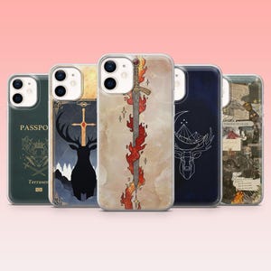 May include: Five phone cases with different designs. The cases display illustrations of a flaming sword, a deer with a cross, a deer with a crescent moon, and a passport. The cases are clear with a pink background.