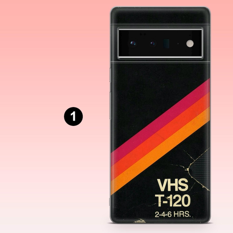 May include: Black phone case with a retro VHS tape design. The case features a diagonal stripe in red, orange, and yellow. The text "VHS T-120" and "2-4-6 HRS." are printed on the case.