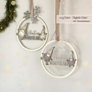 Könnte beinhalten: Zwei Holzornamente mit dem Schriftzug „Winter Wonderland“. Jedes Ornament ist ein weißer Kreis mit einem Zwergen-Design und den Worten „Winter Wonderland“. Eines hat Schneeflocken-Akzente, das andere Stern-Akzente. Die Ornamente hängen an einem Band.