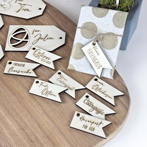 May include: A set of wooden Easter gift tags with various designs and messages, including "Happy Easter", "Easter Greetings", and "Easter Egg Hunt".