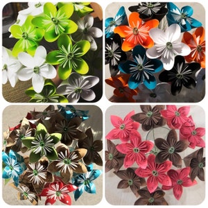 Puede incluir: Una colecci&oacute;n de flores de origami en varios colores, incluyendo blanco, verde, naranja, negro, azul, rosa y marr&oacute;n. Cada flor tiene un dise&ntilde;o de p&eacute;talos detallado y multicapa y un centro verde. Las flores est&aacute;n dispuestas en ramos.