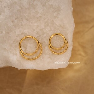 Peut inclure: Deux boucles d'oreilles dorées à double anneau. Chaque boucle d'oreille a un design circulaire avec une forme de croissant perlée plus petite attachée. Le texte "16g (1.2mm) / 8mm,10mm" est visible.