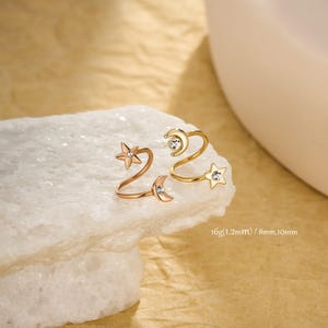 May include: Two ear cuffs with celestial designs, one rose gold and one gold, each featuring a star and crescent moon. The cuffs are embellished with small gemstones. The image text reads: 16g (1.2mm) / 8mm,10mm.