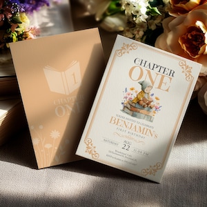 May include: Two invitations with a book theme. One is peach-coloured with a floral design and the words "Chapter One." The other is cream-coloured with the words "Chapter One" and an illustration of a baby sitting on books.