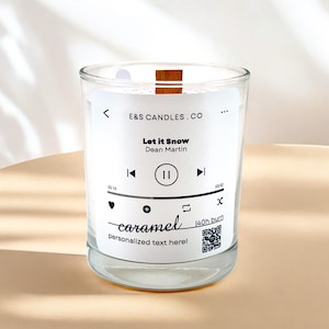 Può includere: Un barattolo di vetro trasparente per candele con un coperchio in legno. L'etichetta presenta un design di lettore musicale con la canzone "Let it Snow" di Dean Martin. La candela è etichettata "caramel" e ha un tempo di combustione di 140 ore.
