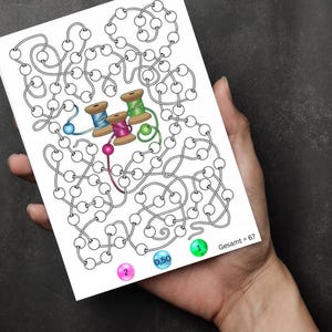 May include: A black and white maze with a blue, green, and pink bead at the start. The maze has a total of 67 circles. The end of the maze has three spools of thread, one with blue thread, one with pink thread, and one with green thread. The numbers 1, 0.50, and 2 are written on the circles at the end of the maze.