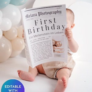 Könnte beinhalten: Ein Baby hält ein Schild im Zeitungsstil mit der Aufschrift "First Birthday" und zusätzlichem Text. Das Baby trägt beige Shorts und ist von weißen und blauen Luftballons umgeben. Auf dem Schild steht auch "Melara Photography".