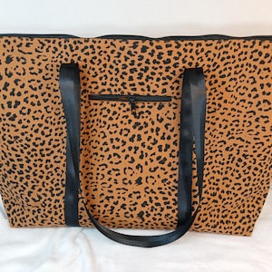 May include: A large brown and black leopard print tote bag with black straps and a zippered pocket on the front.