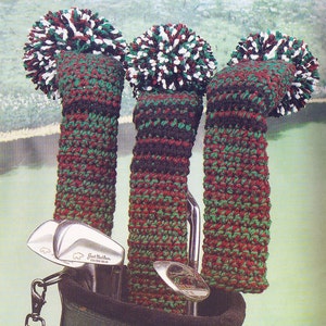 Könnte beinhalten: Drei gehäkelte Golfschlägerbezüge mit Bommeln in Rot, Grün und Weiß. Die Bezüge befinden sich in einer Golftasche mit Golfschlägern. "Designed by Tammie Godfrey" ist auf einem Etikett aufgedruckt.