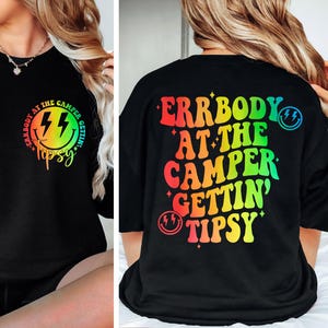May include: Black sweatshirt with a colorful graphic on the front and back. The front features a smiley face with lightning bolts and the words "Errbody at the camper gettin' tipsy". The back has the same text in rainbow colors.