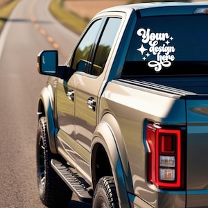 May include: A silver pickup truck with a white decal on the back window that says "Your design here".