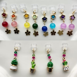 May include: Assortment of colorful charm earrings with flower and cactus designs. The charms are attached to clear plastic earring clips.