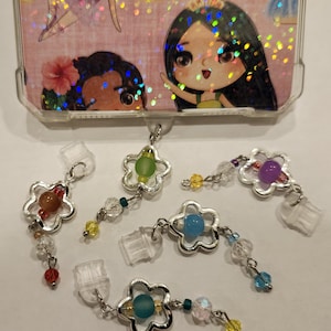 Puede incluir: Cinco colgantes de plata con cuentas de cristal de colores y cuentas de cristal transparentes. Cada colgante presenta un diseño de flor con una cuenta de color diferente en el centro.