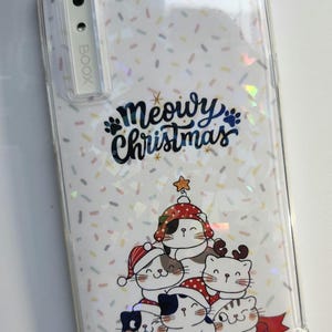 May include: Clear phone case with a festive design. The case features a white background with colorful confetti and a graphic of cats wearing Santa hats and a Christmas tree hat. The text "Meowy Christmas" is also displayed.