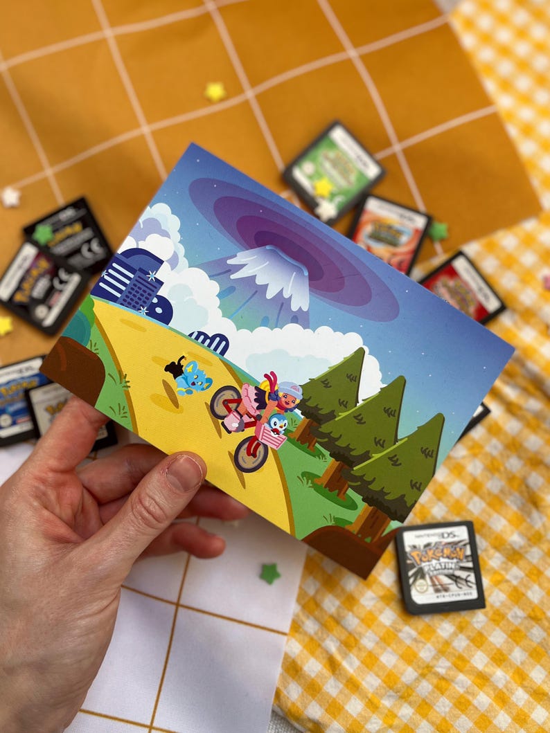 Może przedstawiać: Kolorowa poczt&oacute;wka z kresk&oacute;wkową ilustracją postaci na motocyklu i rowerze, na tle g&oacute;r i chmur. Widoczne są liczne kartridże do gier wideo.