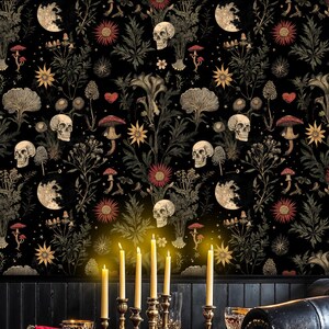May include: A dark dining room with black leather chairs and a wooden table set for a dinner party. The walls are covered in black wallpaper with a floral pattern featuring skulls and moons. There are five lit candles on the table.