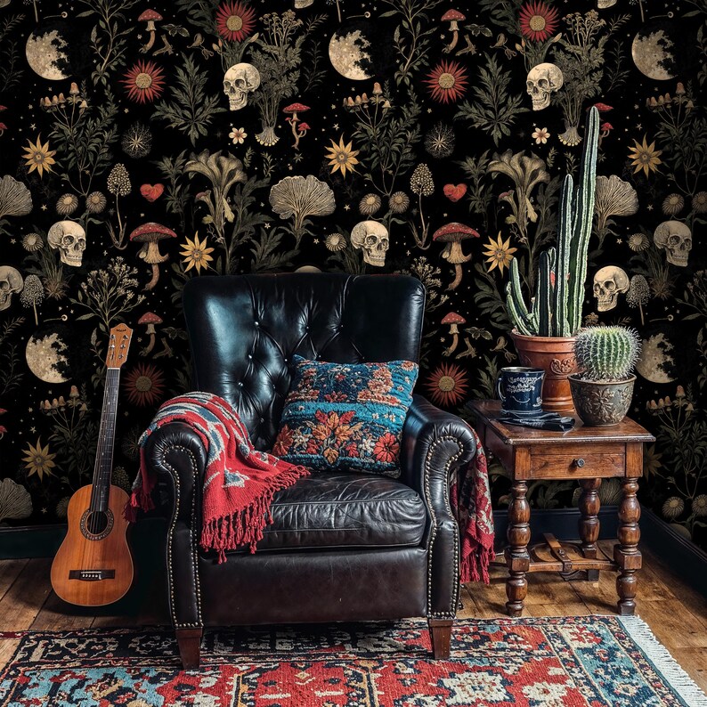May include: A black leather armchair with a red throw blanket and a blue and white patterned pillow sits in front of a wall covered in dark floral wallpaper with skulls and other botanical motifs.