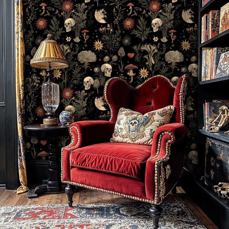May include: A red velvet armchair with gold trim and a skull-patterned pillow sits in a room with black wallpaper featuring a repeating pattern of skulls, flowers, and mushrooms.