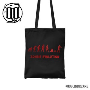 May include: Black tote bag with a red graphic of a zombie evolution timeline. The graphic shows a series of stick figures evolving from a primitive ape to a zombie. The text "Zombie Evolution" is printed below the graphic.