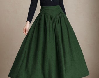 May include: A woman wearing a black turtleneck sweater and a dark green, full-length skirt with a high waist. She is also wearing a red beret and a silver necklace.