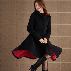 May include: A black hooded coat with a red lining. The coat has a flared skirt and is worn with black boots.