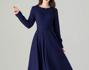 May include: A long-sleeved, navy blue dress with a fitted bodice and a flared skirt. The dress features a round neckline and a defined waist. The fabric appears to be a soft, woven material. The dress is suitable for formal occasions.