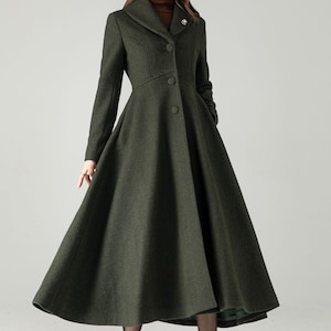 May include: A dark green, long coat with a flared skirt and a tailored bodice. The coat features a notched collar, button closures, and long sleeves. A small brooch adorns the lapel. The coat is a classic style, suitable for formal occasions.