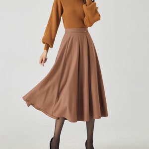 May include: A brown midi skirt with a high waist and a flared silhouette. The skirt is made of a soft, flowing fabric and has a simple, elegant design.