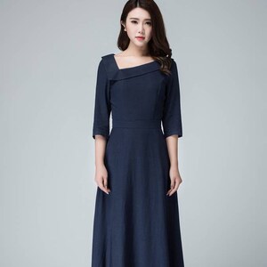 May include: A long, navy blue dress with a square neckline and a fitted bodice. The dress has a flowing skirt and three-quarter sleeves.