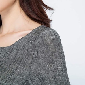May include: Close-up of a gray linen dress with a square neckline and short sleeves.