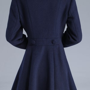 May include: A navy blue coat with a fitted waist and a flared skirt. The coat has two buttons on the back.