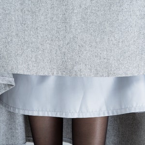 May include: A gray skirt with a light blue underskirt. The skirt is made of a soft, textured fabric.