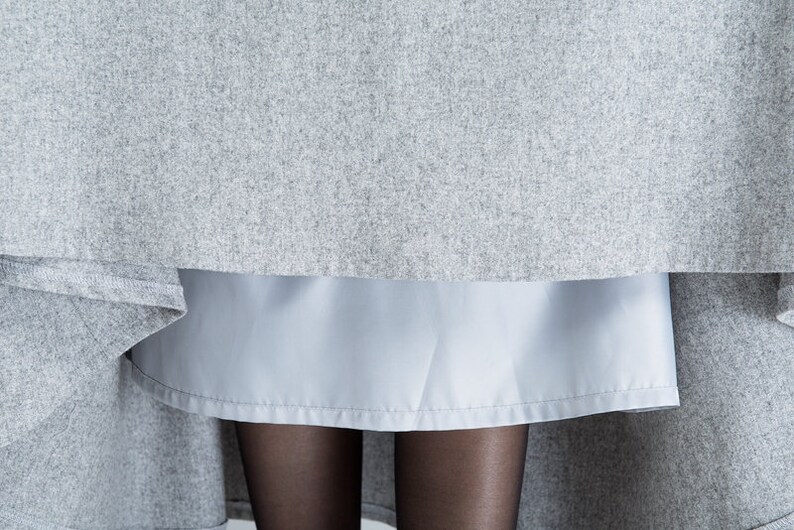 May include: A gray skirt with a light blue underskirt. The skirt is made of a soft, textured fabric.