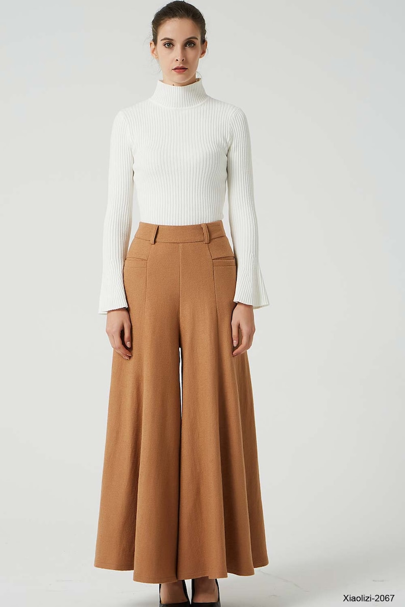 May include: A woman is wearing a white turtleneck sweater and brown wide-leg pants. The pants have a high waist and a wide, flowing leg.