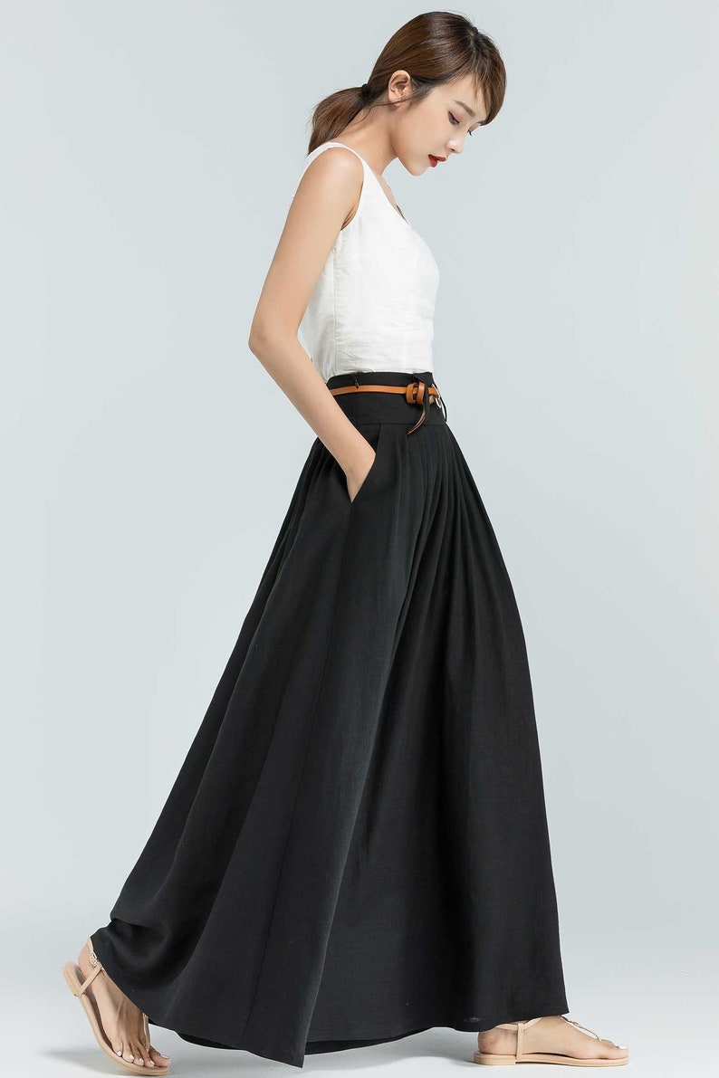 May include: A black maxi skirt with a brown belt. The skirt has pleats and pockets.