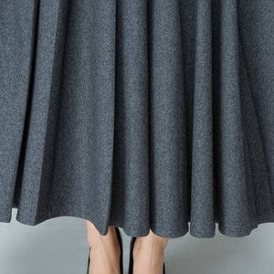 May include: A gray pleated skirt with a smooth, textured fabric.