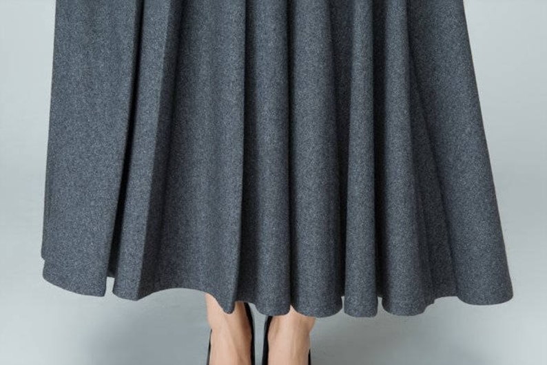 May include: A gray pleated skirt with a smooth, textured fabric.