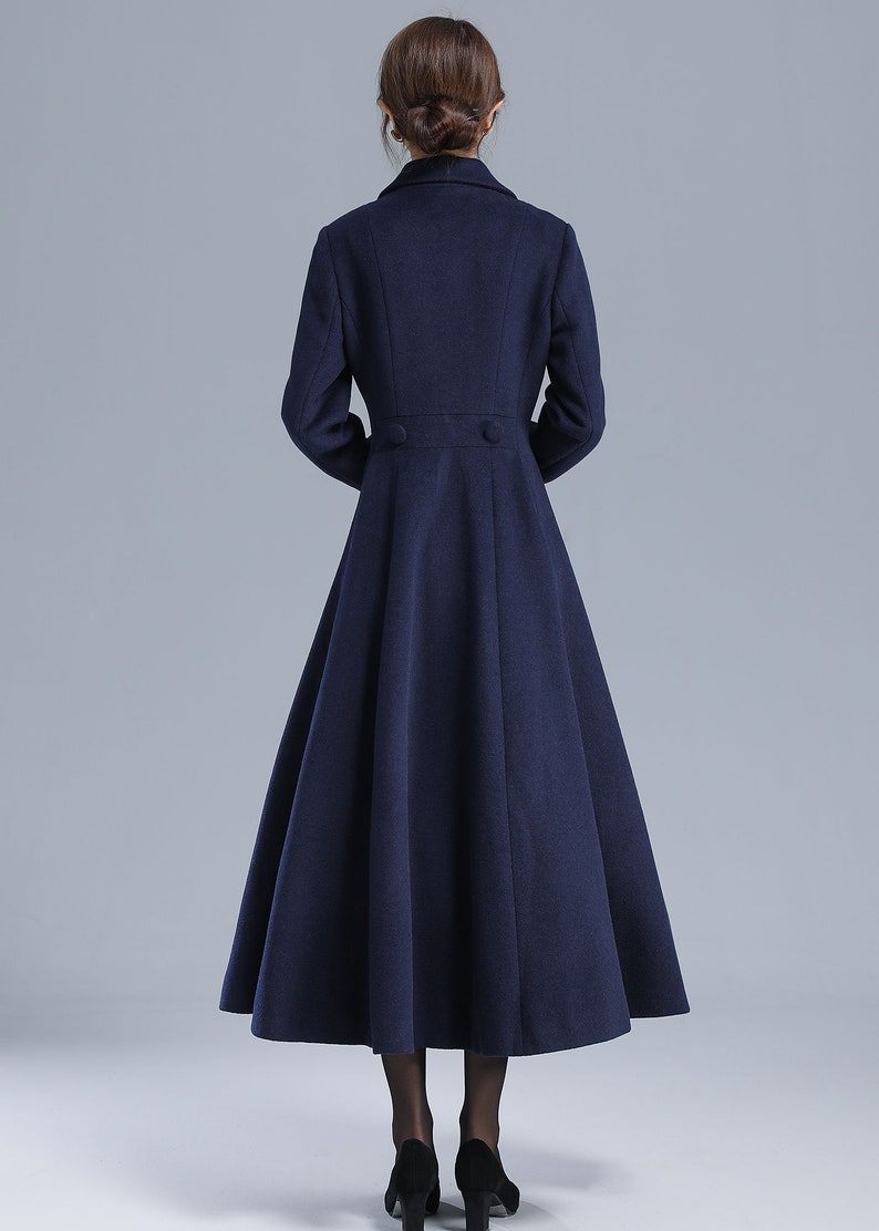 May include: A long, navy blue coat with a flared skirt and a double-breasted closure. The coat has a classic, elegant style.