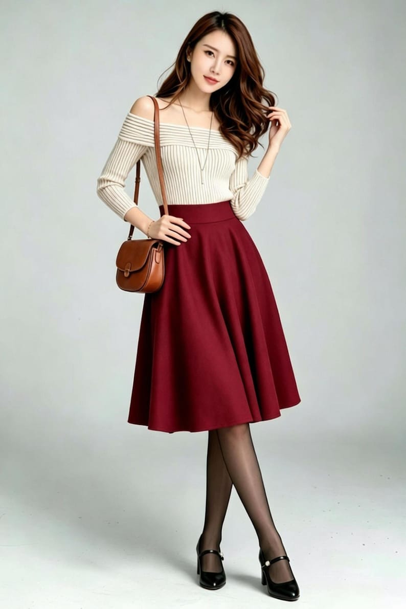 May include: A beige off-the-shoulder ribbed long-sleeve top paired with a high-waisted solid dark red midi skirt. The outfit includes a brown leather crossbody bag, sheer black tights, and black Mary Jane style shoes with a thin ankle strap.