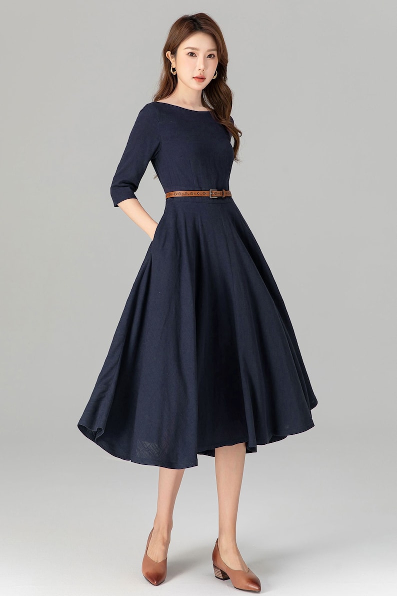May include: A navy blue midi dress with a brown belt and a slightly flared skirt.