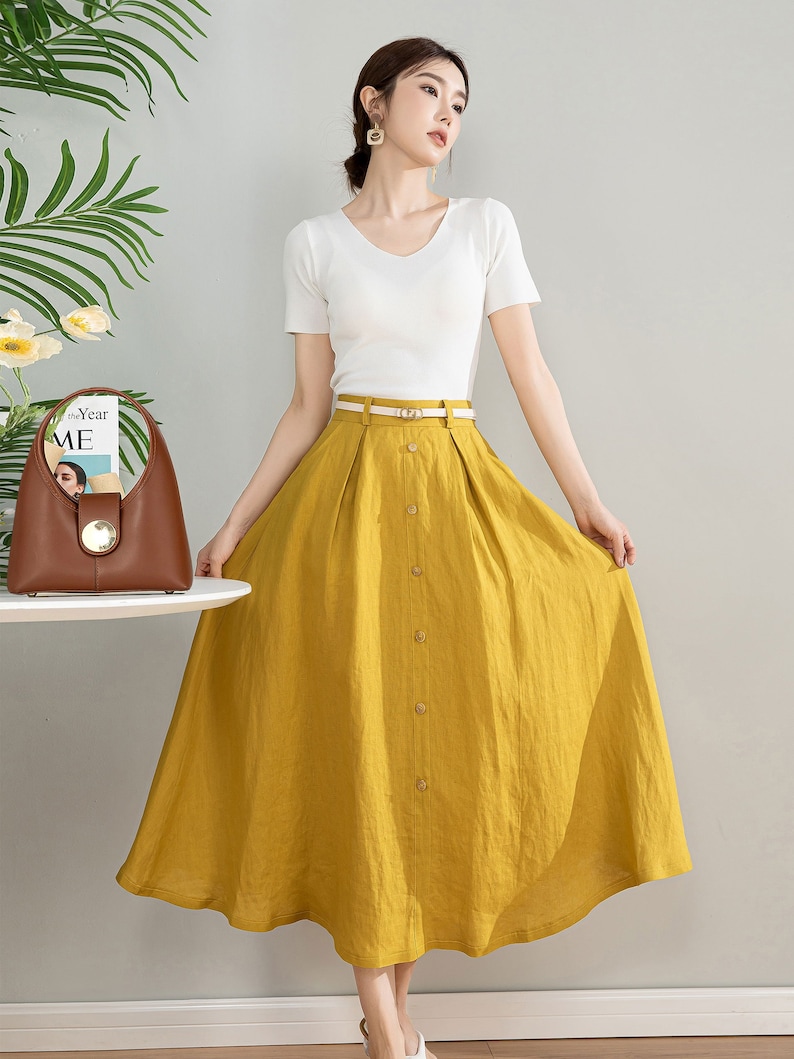 May include: A yellow linen skirt with a button front and a belt. The skirt is midi length and has a flowy silhouette.