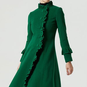 May include: A green wool coat with a ruffled collar and cuffs. The coat has a fitted bodice and a flared skirt.