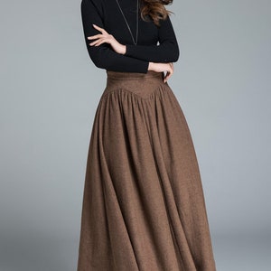 May include: A brown high-waisted skirt with a flared silhouette. The skirt is made of a soft, textured fabric and has a high waistline. The skirt is long and falls to the ankles.